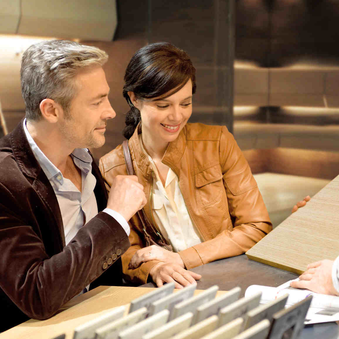 Nainen ja mies valitsemassa saunapaneelin sävyjä pöydän ääressä